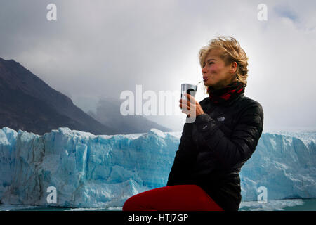 Junge europäische Auftritte Frau trinken Mate auf einem Hintergrund von der Perito Moreno Gletscher in Patagonien, Argentinien, Südamerika Stockfoto