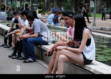 HO CHI MINH CITY, VIET NAM-20. August 2016: Junge asiatische paar spielen Pokemon gehen zusammen auf Smartphone im Tao Dan Park, Ho-Chi-Minh-Stadt, Vietnam Stockfoto