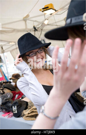 Frau, die versucht einen Hut in The Street Market, Hafenfest, Cardiff Stockfoto