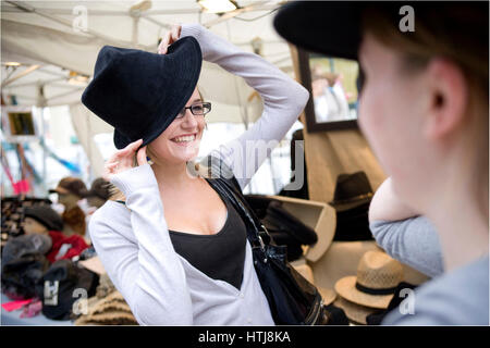 Frau, die versucht einen Hut in The Street Market, Hafenfest, Cardiff Stockfoto