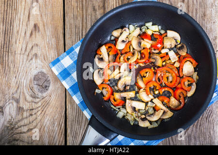 Gebratene Pilze mit Paprika und Zwiebeln in die Pfanne geben. Ansicht von oben. Studio Photo Stockfoto