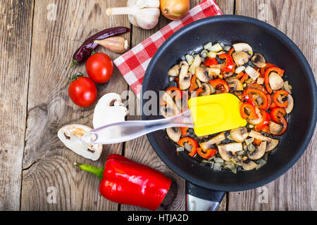 Gebratene Pilze mit Paprika und Zwiebeln in die Pfanne geben. Ansicht von oben. Studio Photo Stockfoto