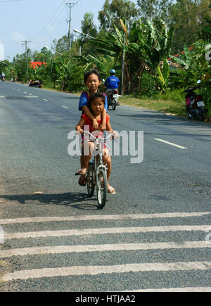 DONG THAP, VIET NAM - Sept. 23, 2014: Zwei nicht identifizierte asiatischen Kind Fahrt Fahrrad auf Landstraße in Gefahr Situation, vietnamesische Kinder Radfahren sehr dang Stockfoto