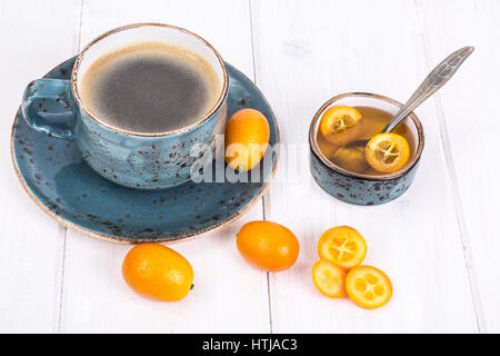 Kumquats, Honig, schwarzer Espresso in Vintage Tasse auf weißem Hintergrund aus Holz. Studio Photo Stockfoto