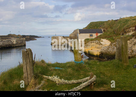 Der kleine Hafen von Ballintoy auf der North Antrim Küste Nordirlands mit seinen Stein gebaut Bootshaus im Meer reflektieren Stockfoto