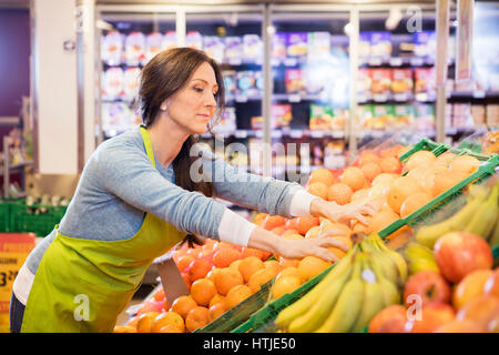 Verkäuferin Anordnen von Orangen im Supermarkt Stockfoto