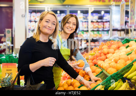 Kunden- und Verkäuferin Auswahl frische Orangen im Store Stockfoto