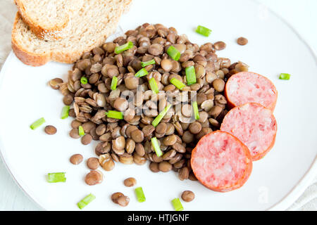 Grüne Linsen mit Hausmacher Wurst (Schlackwurst) auf weißen Teller Stockfoto