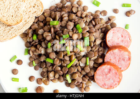 Grüne Linsen mit Hausmacher Wurst (Schlackwurst) auf weißen Teller Stockfoto