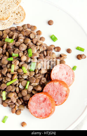 Grüne Linsen mit Hausmacher Wurst (Schlackwurst) auf weißen Teller Stockfoto