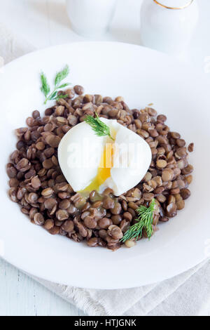 Linsen und weiche pochiertes Ei mit Dill auf weißen Teller - gesundes Bio hausgemachte Mittagessen Stockfoto