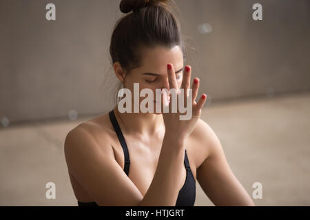 Junge attraktive Frau die Nadi Shodhana Pranayama, graue stud Stockfoto