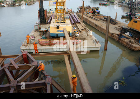 HO CHI MINH CITY, VIET NAM, Group of Asia Arbeiter arbeiten auf der Baustelle, vietnamesische Mann bauen Brücke über Wasser, sie am Stahlgerüst arbeiten Stockfoto