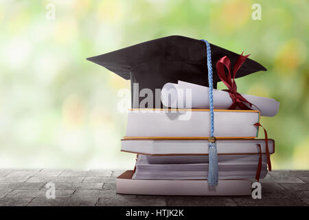 Graduation Hut mit Grad Papier auf einen Stapel von Buch vor verschwommenen Hintergrund Stockfoto