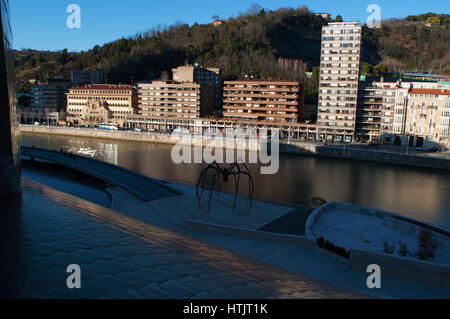 Maman, die Riesenspinne Skulptur von Louise Bourgeois an der Außenseite des Guggenheim Museum Bilbao mit Blick auf die Skyline und den Fluss Nervion Stockfoto
