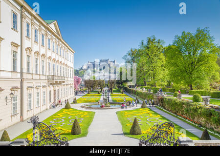 Touristen, die zu Fuß durch berühmten Mirabellgarten mit berühmten Festung Hohensalzburg im Hintergrund an einem sonnigen Tag im Sommer, Salzburg, Österreich Stockfoto