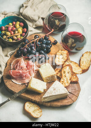 Käse, Oliven, Schinken, Baguette Scheiben, Weintrauben und Rotwein Stockfoto