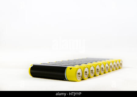 Diagonalen Reihe gelb schwarz AAA alkaline Batterien isoliert auf weißem Hintergrund mit Textfreiraum Stockfoto