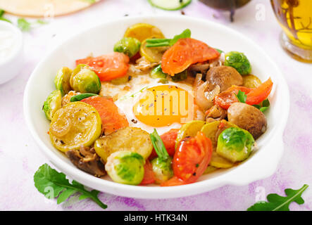Spiegeleier mit Gemüse - Shakshuka und frischer Gurke, Wassermelone Radieschen und Rucola Stockfoto