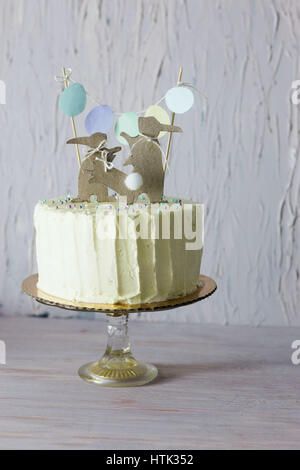 Unter dem Motto Hochzeit oder Geburtstag Osterkuchen, mit Papier-Kaninchen-Silhouetten als Kuchen Topper. Geringe Schärfentiefe. Stockfoto