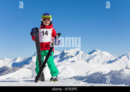 Porträt von glückliches Kind Junge mit Ski in den Händen mit wunderschönen Bergen im Hintergrund Stockfoto