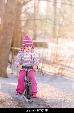 Porträt eines Mädchens sitzen auf einem Fahrrad-Schlitten im Park im winter Stockfoto