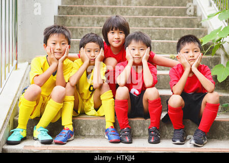 Japanische Kinder im Fußball uniform auf einer Treppe Stockfoto