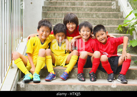 Japanische Kinder im Fußball uniform auf einer Treppe Stockfoto