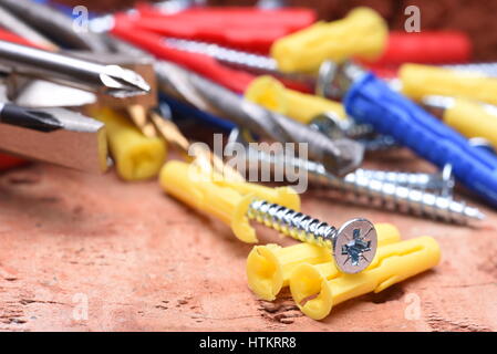Plasctic Dübel Schrauben und Werkzeug auf Ziegel Hintergrund Nahaufnahme Stockfoto