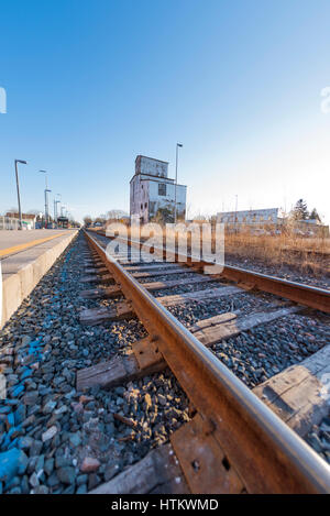 Ein niedrigen Winkel Blick auf Zug verfolgt in einer s-Bahnstation in Stouffville Ontario Kanada. Ein altes Getreidesilo kann in der Ferne gesehen werden. Stockfoto