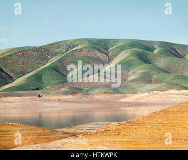 Grüne Hügel und Niedrigwasser bei San Luis Reservoir in Kalifornien. Stockfoto