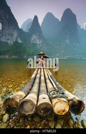 Kormoran Fischer sitzt auf seinem Bambusfloß am Ufer des Li Flusses nahe dem Dorf Xingping, Region Guangxi, China. Stockfoto