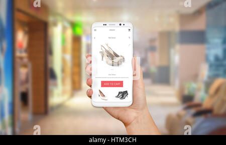 Online-Shop auf dem Handy-Display. Moderne weiße Smartphone mit runden Kanten in Mädchen Hand. Einkaufszentrum im Hintergrund. Stockfoto