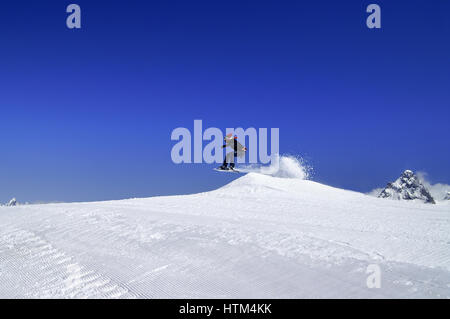 Snowboarder springen im Snowpark im Skigebiet auf Sonne Wintertag. Kaukasus-Gebirge, Region Dombay. Stockfoto