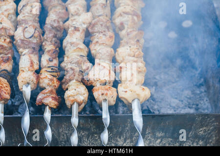 Zubereitung von Fleisch am Feuer Draufsicht, Schaschlik am Spieß, Rauch auf dem Grill. Stockfoto