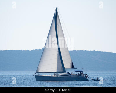Eine Jacht Segelboot Boot mit weissen Segeln Segeln Segeln auf dem Meer Ozean Mittelmeer unter einem blauen Himmel auf ruhigen Gewässern vor der Küste von Kroatien Stockfoto
