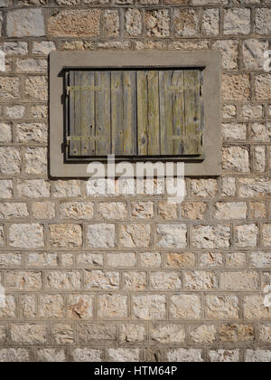 Ein altes Fenster mit Fensterläden aus Holz Holz Verschluss in einem spitzen Stein Wand mit groben Mörtel nach Kroatien Stockfoto