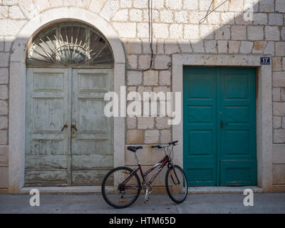 ein Fahrrad gelehnt Stein aufgestützt Blockwand zwischen alten grün bemalten Tür Türen in Kroatien Stockfoto