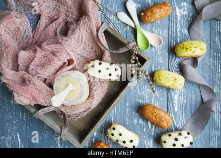 Eclairs mit Schokolade und Sahne auf dunklem Hintergrund. Traditionelles französisches Dessert. Ansicht von oben. Stockfoto