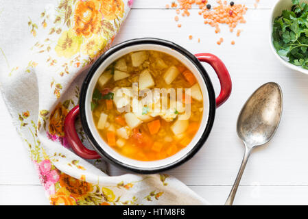 Draufsicht der vegetarische Erbsensuppe mit roten Linsen und frischer Petersilie auf weißer Holztisch Stockfoto