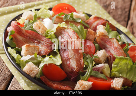 Würziger Salat Croutons, Speck, Tomaten und Kopfsalat hautnah auf einem Teller auf den Tisch. Horizontale Stockfoto