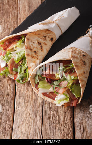 Speck und Salat eingewickelt in Pita Brot Nahaufnahme auf dem Tisch. vertikale Stockfoto