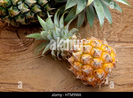 Frische asiatische kleine Ananas auf Holzplatte im Sonnenlicht im freien Stockfoto