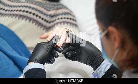 Closeup Aufnahme einer Frau in einem Nagelstudio erhalten eine Maniküre von einer Kosmetikerin mit Nagelfeile. Frau immer Nagel Maniküre. Stockfoto