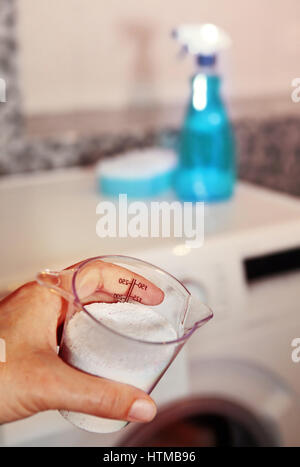 Hand der Frau, das Waschmittel in der Waschmaschine füllt Stockfoto