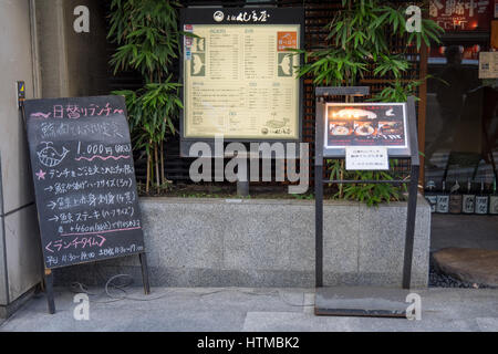 Eine Tafel und gedruckte Speisekarte draussen ein Restaurant das Walfleisch in Shibuya Tokio serviert. Stockfoto