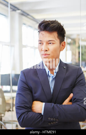 Junge asiatische als Unternehmer denken mit Skepsis und Arme gekreuzt Stockfoto