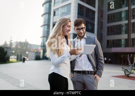 Geschäftsleute, walking im Freien und mit Handys Tabletten Stockfoto