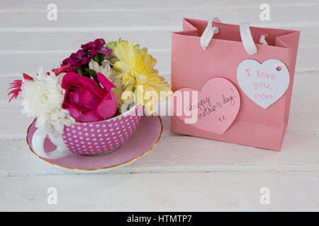 Nahaufnahme der Papiertüte mit Meldung und frische Blumen auf Holzuntergrund Stockfoto