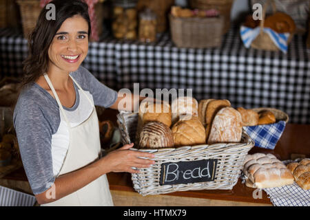 Porträt von Mitarbeiterinnen mit Weidenkorb an verschiedenen Brotsorten am Schalter in Bäckerei Stockfoto